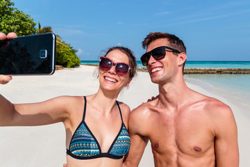 Happy young couple taking a selfie. Tropical island as background