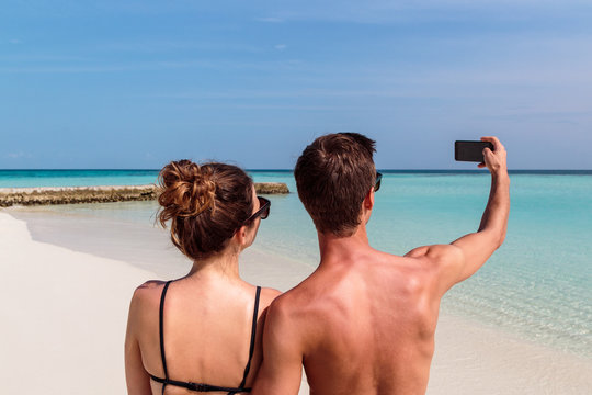 Happy young couple taking a selfie. Tropical island as background