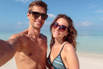 Obraz premium happy young couple taking a selfie, clear blue water as background. hug