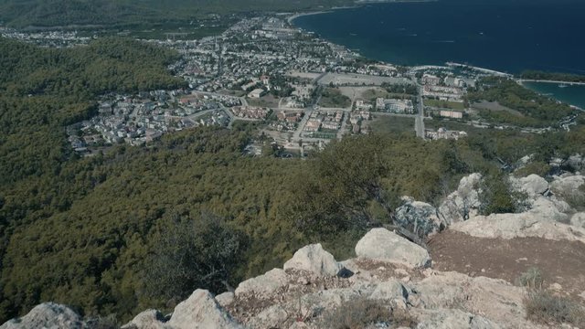View From The Height Of The City On The Sea.City Along The Sea View From Above. View From Table Mountain Top Over Kemer City.View From Big Rock On Sea Bay With Settlement And Boats In Wavy Blue Sea 