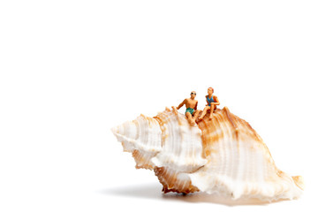 Miniature people  wearing swimsuit relaxing on  seashells  on white background , Valentine's Day concept