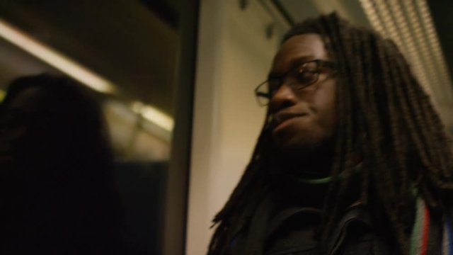 Young man with dreadlocks takes a seat on a train