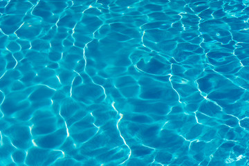 Blue water in swimming pool background. Ripple Water in swimming pool with sun reflection. Blue...