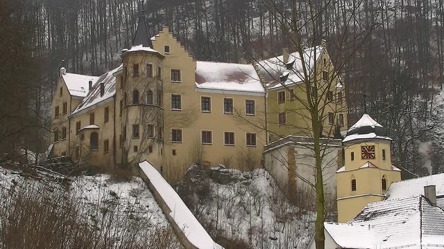 Little castle in the winter near the forest with smoking chimney