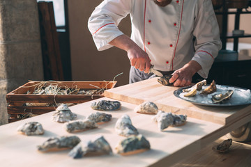 Opening the hollow and flat oysters. Chef opens oysters in the restaurant.