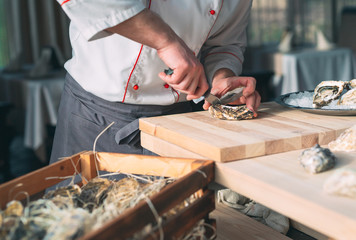 Opening the hollow and flat oysters. Chef opens oysters in the restaurant.