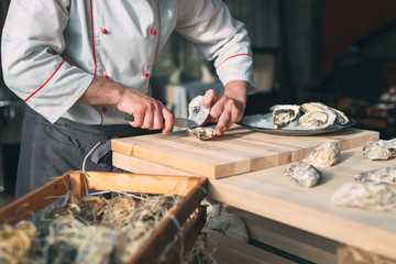 Opening the hollow and flat oysters. Chef opens oysters in the restaurant.