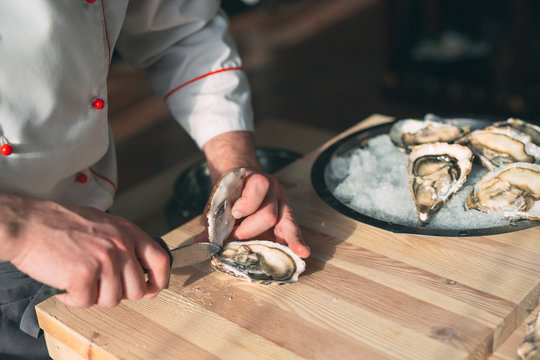 Opening the hollow and flat oysters. Chef opens oysters in the restaurant.