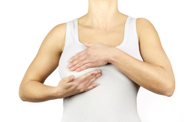 Woman white shirt examining her breast for lumps or signs of breast cancer