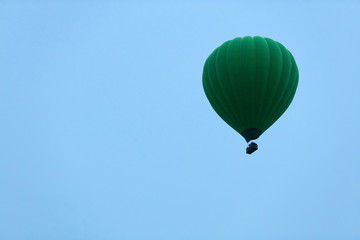 Ballooning. Green Hot Air Balloon Flying High In Blue Sky