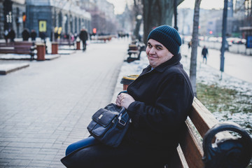 Young large man in coat and hat walks at city streets. Life of big young people, lifestyle 