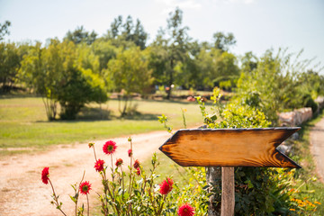 Retro wooden sign with red flowers at the countryside
