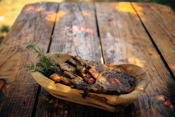 Delicious grilled pork and chicken meat with rosemary on the traditional wooden dish on the old wooden table