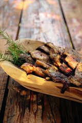 Delicious grilled pork and chicken meat with rosemary on the traditional wooden dish on the old wooden table