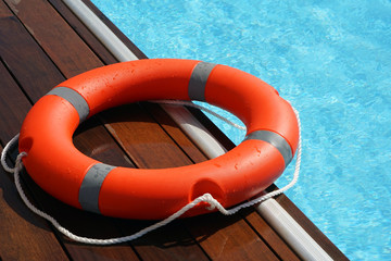 The red life ring lies on the wooden floor of the swimming pool. Life cycle, floating above the...