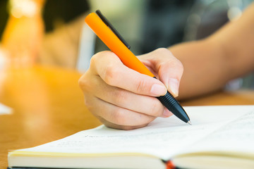 Female hands with pen writing on notebook