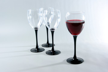 One glass of red wine and three empty glasses