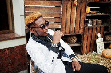 Chic handsome african american man in white suit sitting on chair.