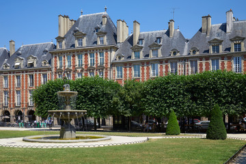 Obraz premium Place des Vosges, red facade buildings and garden in Paris in a sunny summer day, clear blue sky
