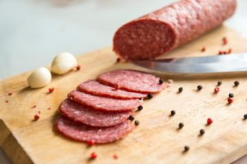 sliced salami slices with spices and garlic on wooden Board, knife