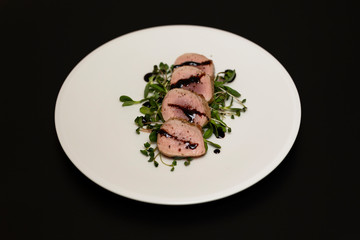Pork tenderloin with fresh herbs on white plate