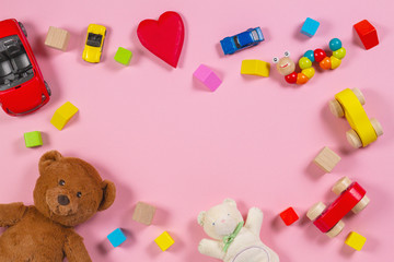 Baby kids toys frame with teddy bear, wooden toy car, colorful bricks on pink background. Top view