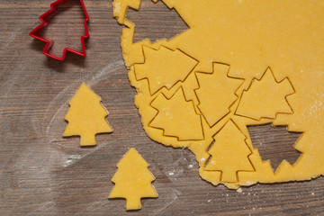 Preparation of ginger biscuits. Cutting figured cookies in form of Christmas tree. New Year's Eve symbol.