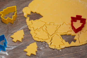 Preparation of ginger biscuits. Cutting figured cookies in form of Christmas tree. New Year's Eve symbol.