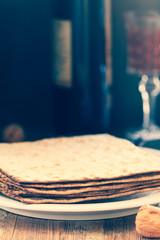 White plate with matzah or matza on a vintage wood table presented as a Passover seder feast or meal with with dark marble or stone background