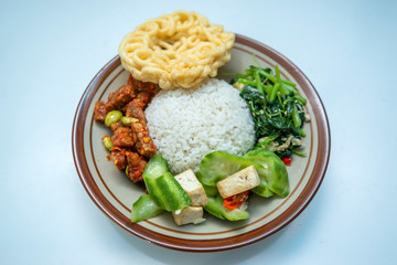 Indonesian home made style food nasi campur or mixed rice with krupuk, tempe balado, pete, sayur bayam, tahu dan sayur oyong