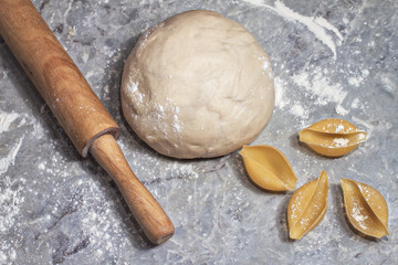 bowl of raw dough with a rolling pin and shells of durum wheat