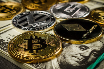Bitcoin and other cryptocurrency coins on packs of dollars