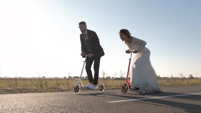 Young couple ride a scooter in road at sunset