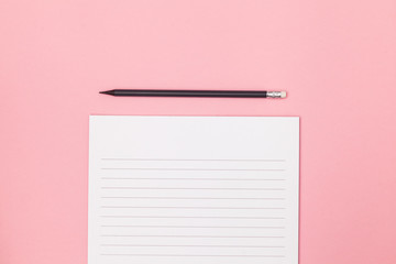 Blank page in a line with black pencil. Plans and goals for the year. Freelancer workplace concept. Top view with copy space for input the text. Flat lay, colored pink background.