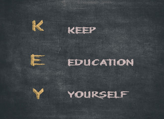 KEY acronym - KEEP EDUCATING YOURSELF. Educational concept with different color sticky notes and white chalk handwriting on a blackboard