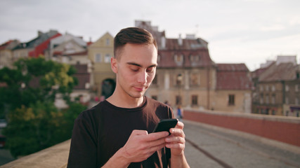 A young man using a phone in the city street. Close-up shot. Soft focus