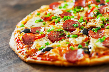 Pizza with Chicken meat, Mozzarella cheese, pepperoni, tomato, olive, salami. Italian pizza on wooden background