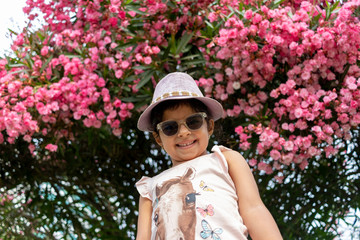 Beautiful girl with glasses and hat in front of flowers