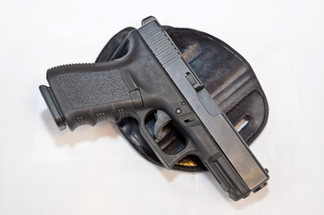 A black 9mm pistol laying in top of a black holster with a white background