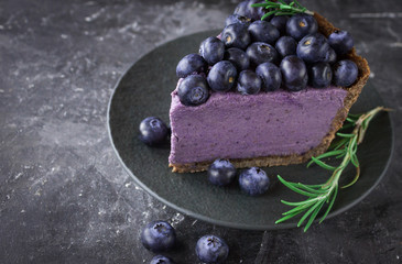 Blueberry vegan cheesecake. Dark photo on black background