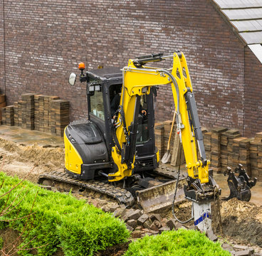 Digger Machine Equipped With A Drill Working On Constructing A Garden