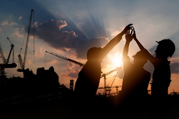 Engineer teamwork, silhouette of construction worker team touching hand together for power at...