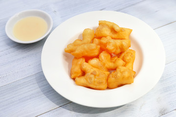 Deep-fried dough stick with sweetened condensed milk on wooden background. 