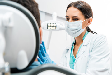 female dentist in mask examining patient