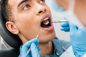 close up of african american man with open mouth during examination in dental clinic - obrazy, fototapety, plakaty