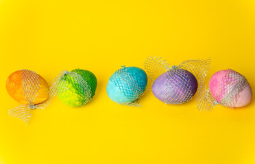 colorful, hand-painted, pastel Easter eggs on a bright, yellow, spring background