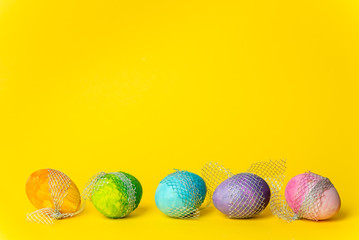 colorful, hand-painted, pastel Easter eggs on a bright, yellow, spring background