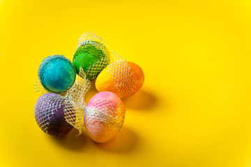 colorful, hand-painted, pastel Easter eggs on a bright, yellow, spring background