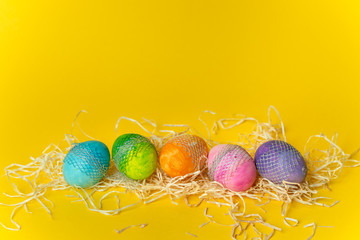 colorful, hand-painted, pastel Easter eggs on a bright, yellow, spring background