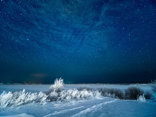Snow at field and starry winter sky. Snowy moonless winter night at northen of Europe.